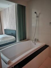 Modern bathroom with bathtub and view into bedroom