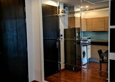 View of kitchen area with washing machine from a wood-floored hallway with mirrored closet doors