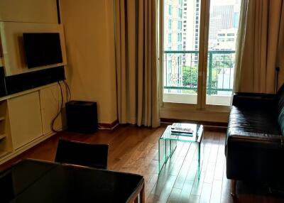 Cozy living room with a sofa, coffee table, wall-mounted TV and a balcony view