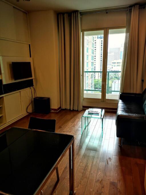 Cozy living room with a sofa, coffee table, wall-mounted TV and a balcony view