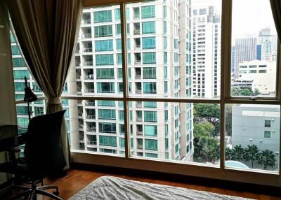 Bedroom with large windows offering a view of city buildings