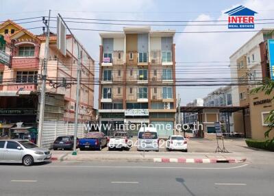 Street view of a multi-story building with a real estate advertisement