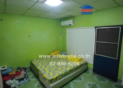 Bedroom with green walls, a bed with patterned bedsheet, and a door with a blue frame