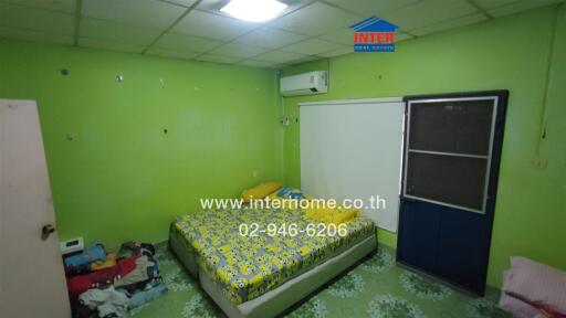 Bedroom with green walls, a bed with patterned bedsheet, and a door with a blue frame