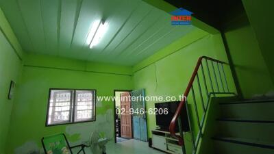 Living room with lime green walls, a television, and stairs leading to an upper level