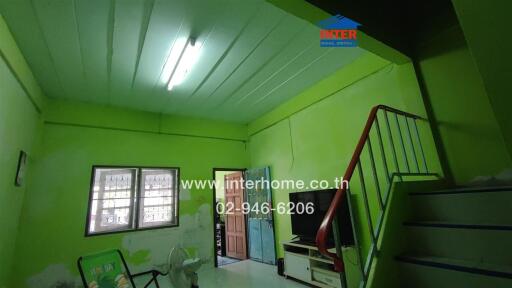 Living room with lime green walls, a television, and stairs leading to an upper level