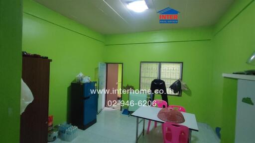 Main room with green walls, table with chairs, and some furniture