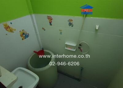 Bathroom with green and white walls, stickers, and basic amenities