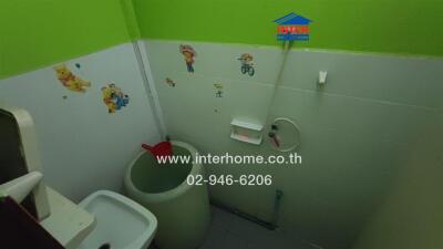 Bathroom with green and white walls, stickers, and basic amenities