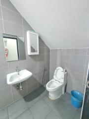 Modern bathroom with sink, mirror, toilet and a blue trash bin