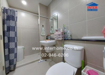 Modern bathroom with light brown tiles, a mirror, and various toiletries.