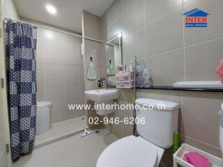 Modern bathroom with light brown tiles, a mirror, and various toiletries.