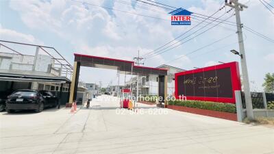 Entrance of a residential area with security gate and signage