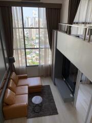 Modern living room with floor-to-ceiling windows, a loft bed, a sectional sofa, and a city view