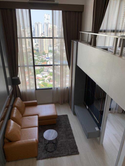 Modern living room with floor-to-ceiling windows, a loft bed, a sectional sofa, and a city view