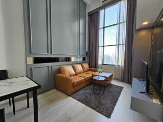 Modern living room with a large window, brown leather sofa, and TV