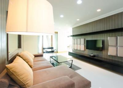 Well-lit modern living room with a large sofa, TV, and accent lighting