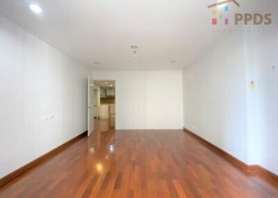 Spacious main living area with wooden flooring and an open door leading to the kitchen