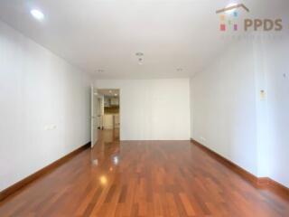 Spacious main living area with wooden flooring and an open door leading to the kitchen