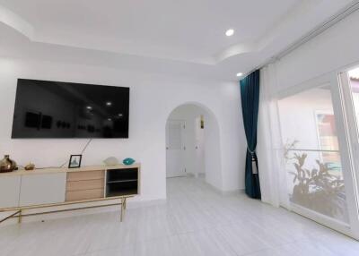 Modern living room with large TV and white furniture