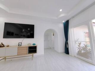 Modern living room with large TV and white furniture
