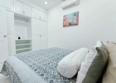 Modern bedroom with white built-in wardrobes, air conditioner, and artwork