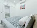 Modern bedroom with white built-in wardrobes, air conditioner, and artwork