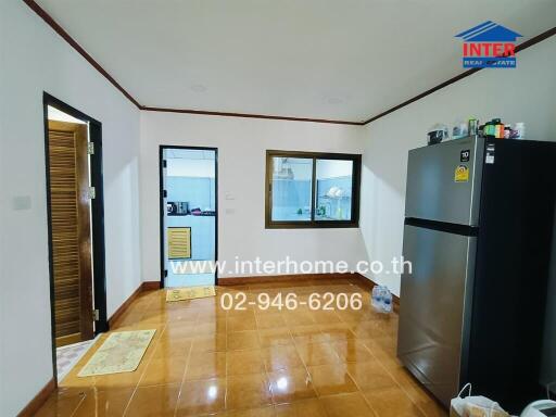 Bright kitchen with refrigerator, tile floor, and adjacent rooms.