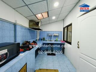 A view of the kitchen with blue tiling, modern appliances, and storage spaces.