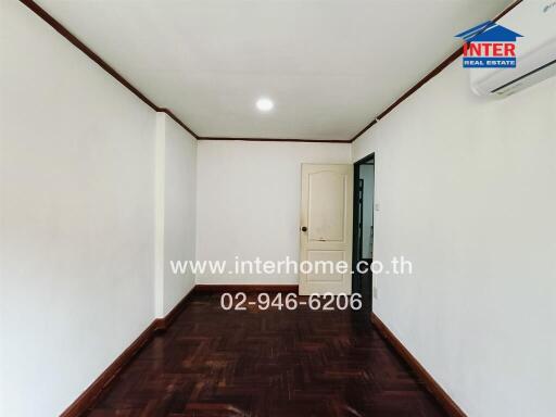 Empty room with wooden floor, white door, air conditioning, and ceiling light