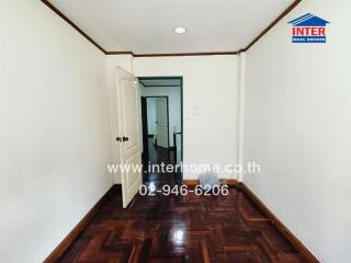 Unfurnished bedroom with wooden flooring and white walls