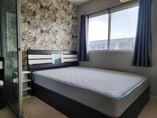 Modern bedroom with a large bed, stone accent wall, and large window