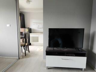 photo of a living area with a TV on a stand and a partially visible dining area