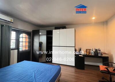 Spacious bedroom with blue bedspread, large wardrobe, air conditioning, and study area