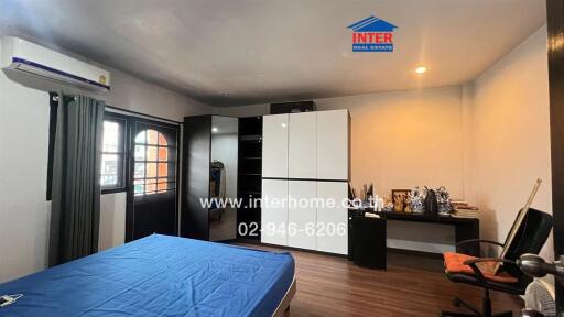 Spacious bedroom with blue bedspread, large wardrobe, air conditioning, and study area