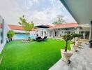 Spacious outdoor area with artificial grass, potted plants, and a swimming pool.