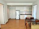 Modern kitchen with wooden flooring, dining table, and white cabinets