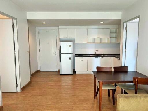 Modern kitchen with wooden flooring, dining table, and white cabinets