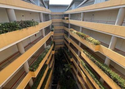 View of a multi-story apartment building with a central courtyard featuring greenery and a small fountain