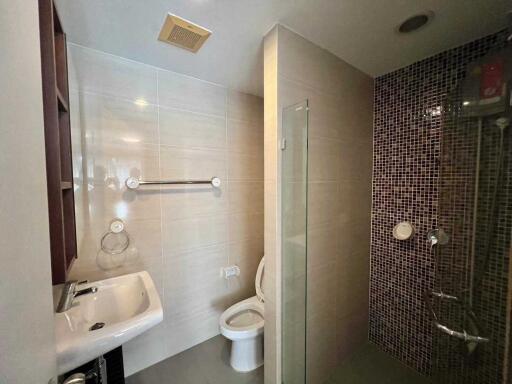 Modern bathroom with toilet, sink, and shower area