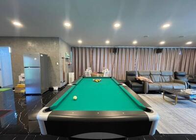 Modern living area with a pool table, couch, refrigerator, and curtains