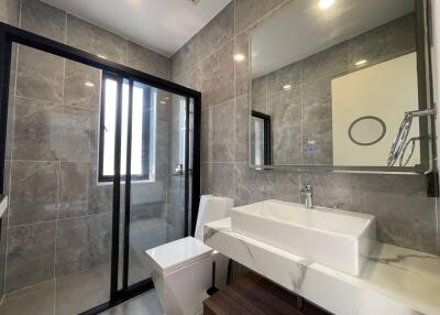 Modern bathroom with large mirror, glass shower, and tiled walls