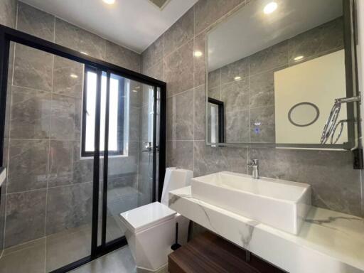 Modern bathroom with large mirror, glass shower, and tiled walls