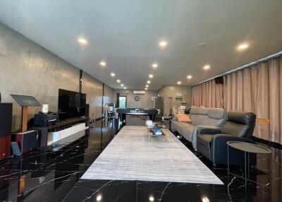 Spacious modern living room with black tiled floor, large rug, comfortable seating, and entertainment setup