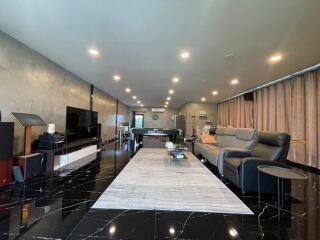 Spacious modern living room with black tiled floor, large rug, comfortable seating, and entertainment setup