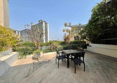 Outdoor patio area with table and chairs, greenery, and a city view