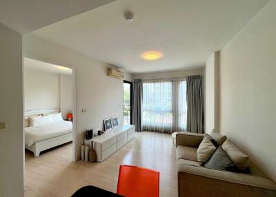 A modern living room connected to a bedroom with natural light and modern furniture