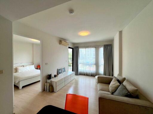 A modern living room connected to a bedroom with natural light and modern furniture