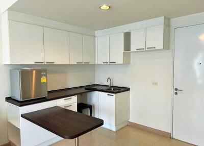 Modern kitchen with white cabinets, a stainless steel refrigerator, and a small dining area.