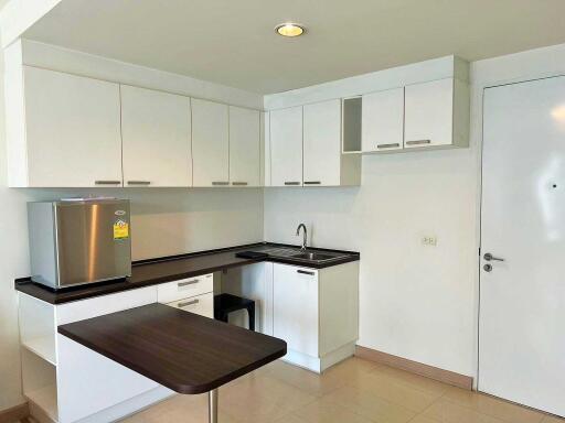 Modern kitchen with white cabinets, a stainless steel refrigerator, and a small dining area.